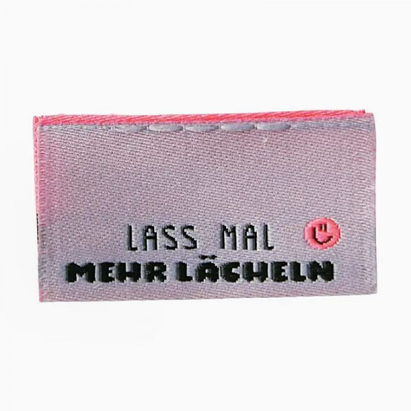 Foldet stofmærker "Mehr Lächeln" 30 x 17 mm